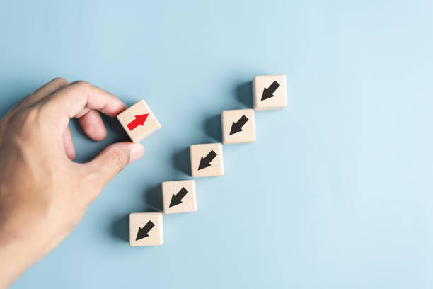 istock Hand holding wood block with Red arrow and different direction facing opposite direction with black arrow for business disruption and technology transformation and different thinking idea concept. 1504391404