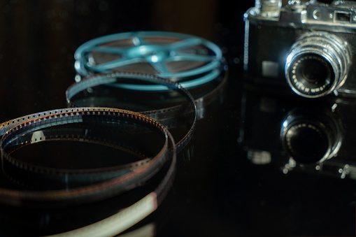 Unwound narrow retro film strip on a light reel on the background texture of the table. Cinema accessories for watching movies