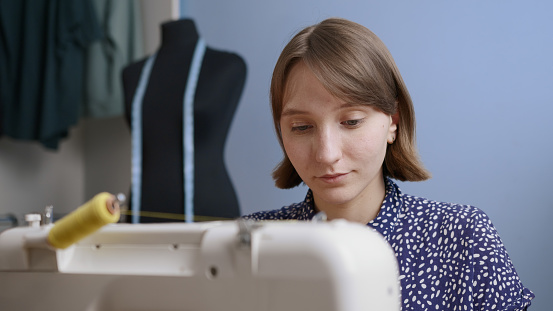 Young european woman sew at home close up