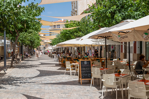 Mahón, Spain, June 22, 2023; Cozy street with many terraces and restaurants in the center of the Spanish town of Mahon on the island of Menorca.