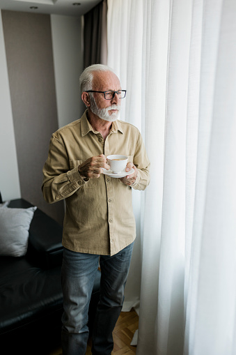 Senior adult man drinking coffee and relaxing at home