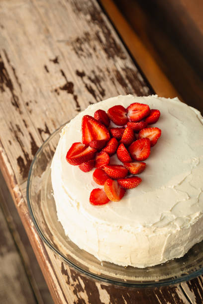 istock White cake decorated with strawberries on a wooden background. 1504484334