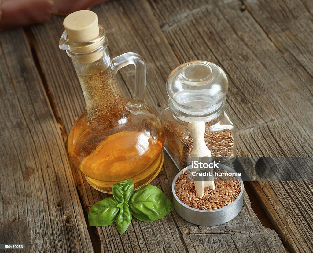 Dried linseed with macerated oil Dried linseed with macerated oil isolated on wooden table Cooking Oil Stock Photo