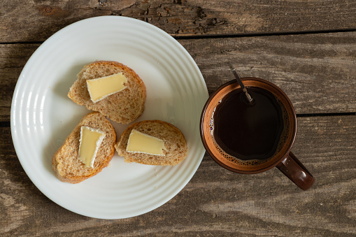 hot black tea and white bread with butter and cheese on an old table