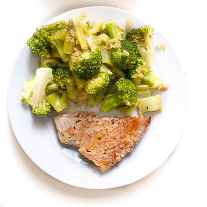 High angle view of tuna fish with broccoli at home on white plate for lunch ready to eat.