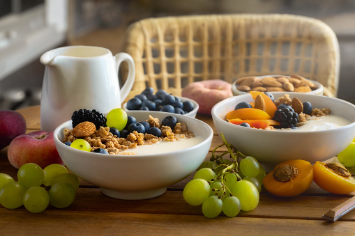 Two healthy breakfast bowl with granola fruits Greek yogurt and berries on wooden table in a rustic home kitchen. Weight loss, healthy lifestyle and eating concept