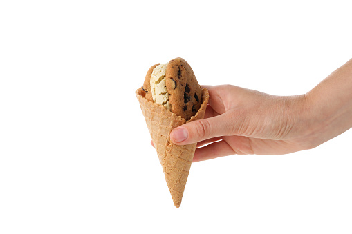 Female hand holds cone with cookies with ice cream, isolated on white background