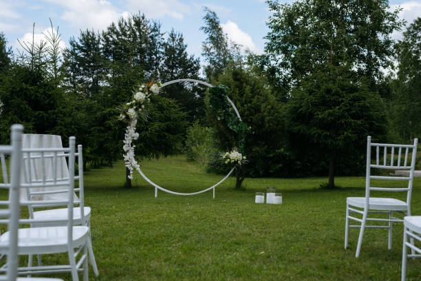istock White round arch with flowers and white chairs. Preparing for wedding ceremony. Space for text. 1504626244