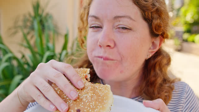 Woman Prepares Her Burger And Takes a Scrumptious Bite