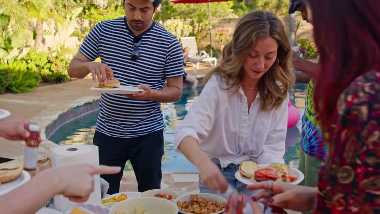 Friends Putting Food On Their Plates At BBQ