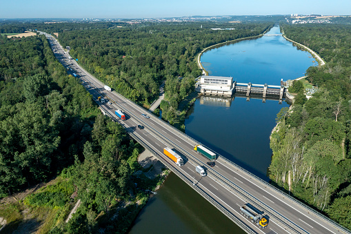 Aerial view of a rural highway with car and truck traffic and a canal with a water power plant.