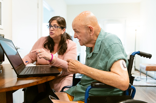 A senior man with disabilities talks with a home caregiver