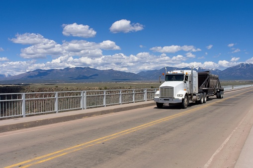 Truck crosses over the Rio Grand Gorge bridge. Blue sky background with copy space in foreground. The bridge has a span over 1200 feet and is the 10th highest bridge at over 600 feet.