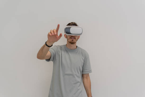istock Futuristic man wearing virtual reality glasses interacts with the air in an isolated gray background. 1504691012