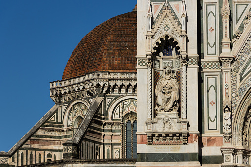 Detail of decorations on the facade of Florence Cathedral, Basilica di Santa Maria del Fiore with behind Brunelleschi's dome. Florence, Italy