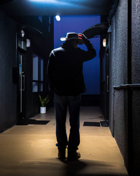 istock Silhouette man standing in a dark narrow archway under ceiling light. Vertical format. 1504721860