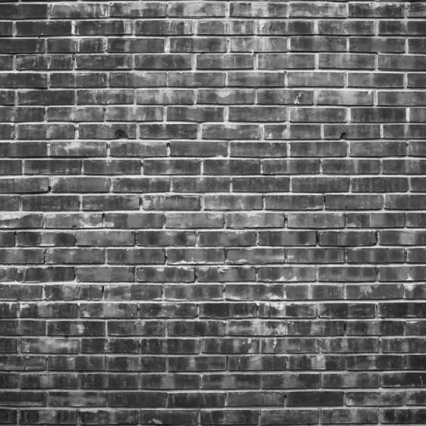 istock Grayscale backdrop with old realistic black brick wall. Minimal fragment of brickwall close-up. Minimalist monochrome background with wall of gray bricks in different shades. Simple wall texture. 1504759478