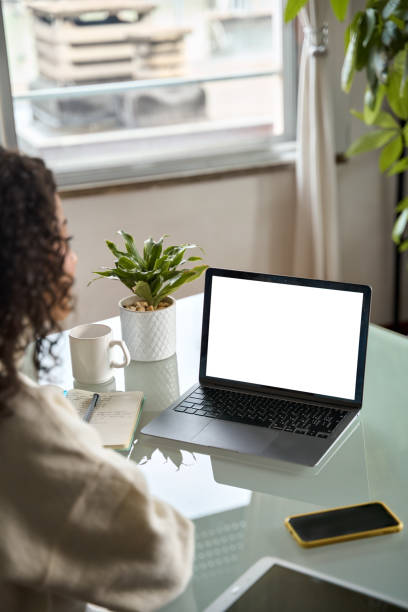 istock Over shoulder vertical view of girl elearning looking at mock up laptop screen. 1504763499
