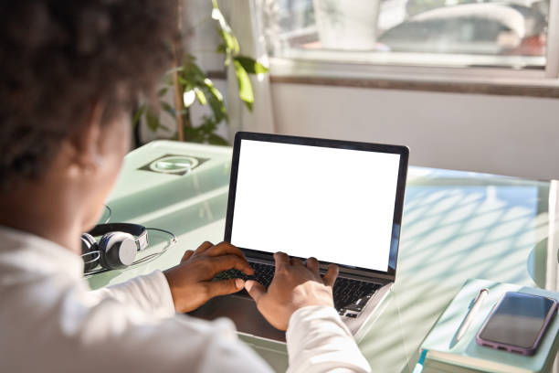 istock Over shoulder view of gen z African student using laptop mock up white screen. 1504763513