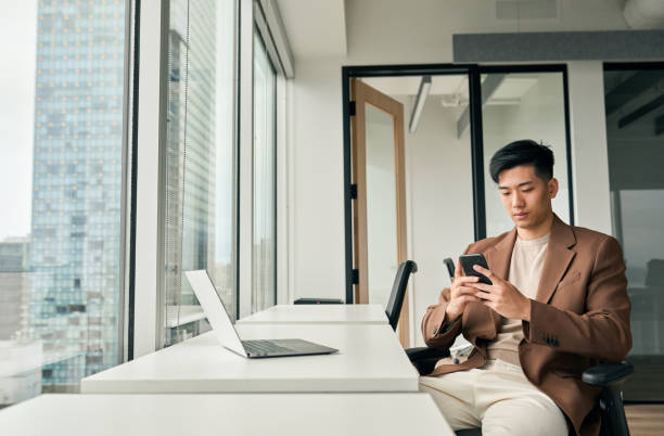 istock Young busy Asian business man working using mobile and laptop in office. 1504763539