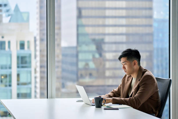 istock Young serious Asian business man working on laptop using computer in office. 1504763752