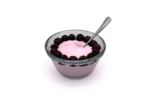 Glass bowl full of strawberry yogurt with frozen blueberries