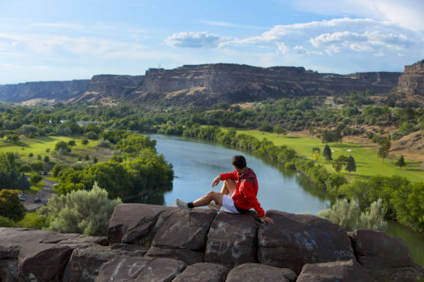 istock Teen boy rests on a rock overlooking the Snake River. 1504779687