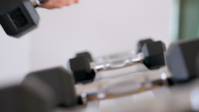Black dumbbell row set. Hand pickup metal dumbbells on rack in sport fitness gym, Weight training equipment