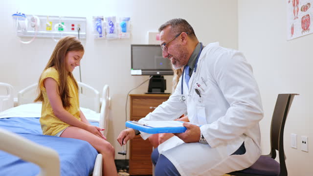 Doctor checking reflexes of a 9 year old girl in the exam room