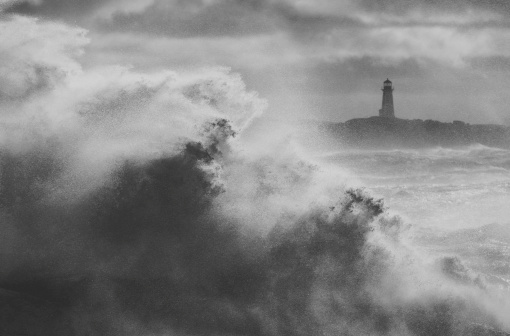 Heavy surf fueled by a powerful Winter storm slams the coastline at Peggy's Cove Lighthouse, Nova Scotia.  Toned black and white image.