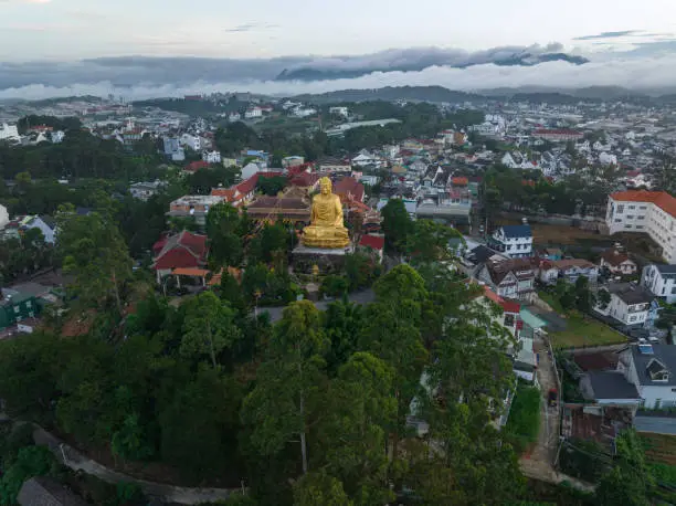Drone view golden buddha statue on Van Hanh monastery in early morning, Da Lat city, Lam Dong province, central highlands Vietnam