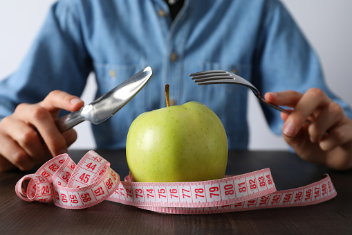Concept of weight loss and healthy nutrition with apple and measuring tape