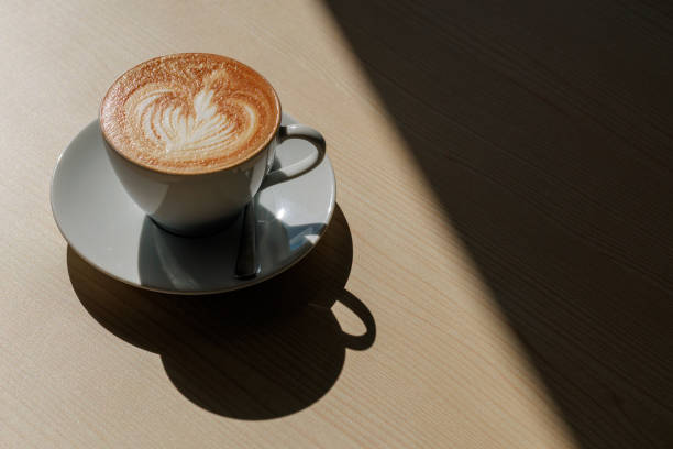 istock A cup of coffee latte on a wooden table creates a shadow in the strong sunlight. 1504950922