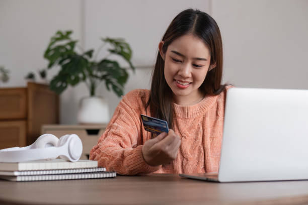 Image of young asian woman order online, shopping from home. Girl enter credit card info on webside to make purchase, using laptop to shop, paying bills with computer. imagen de una joven asiática ordenando en línea, comprando desde casa. chica ingrese la información de la tarjeta de crédito en el lado web para realizar la compra, use la computadora portátil para comprar, pague facturas con la computadora