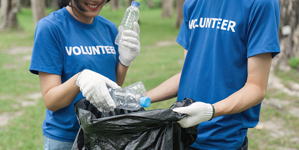 Volunteer hands, cleaning up and trash bag for pollution, carbon footprint and eco friendly in park. Closeup and plastic collection outdoor, sustainability and charity service for environment.