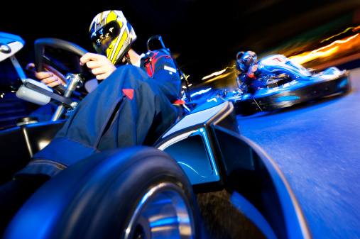 Two go-cart drivers batteling in a competitive race on an indoor circuit