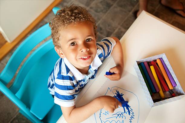 niño pre-escolar jugando con una caja de crayons - colorear fotografías e imágenes de stock