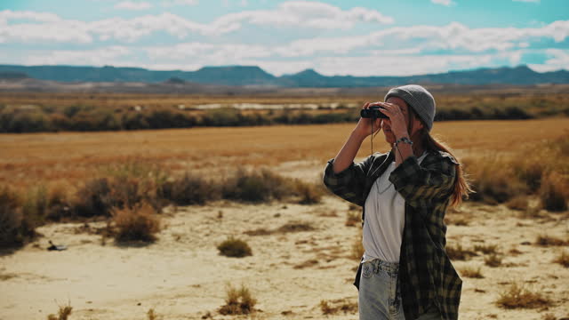 WS Woman uses binoculars to observe the desert and rocky mountains in Morocco