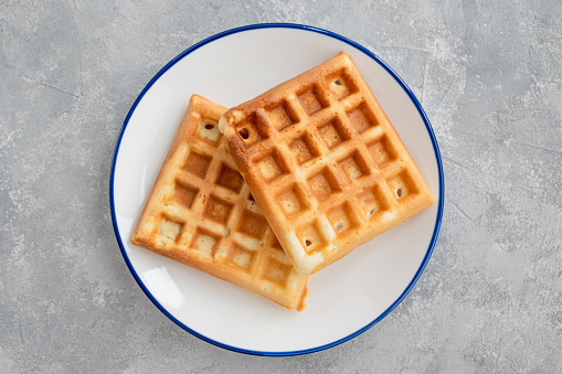Waffles with banana, whipped cream and salty caramel on a gray concrete background