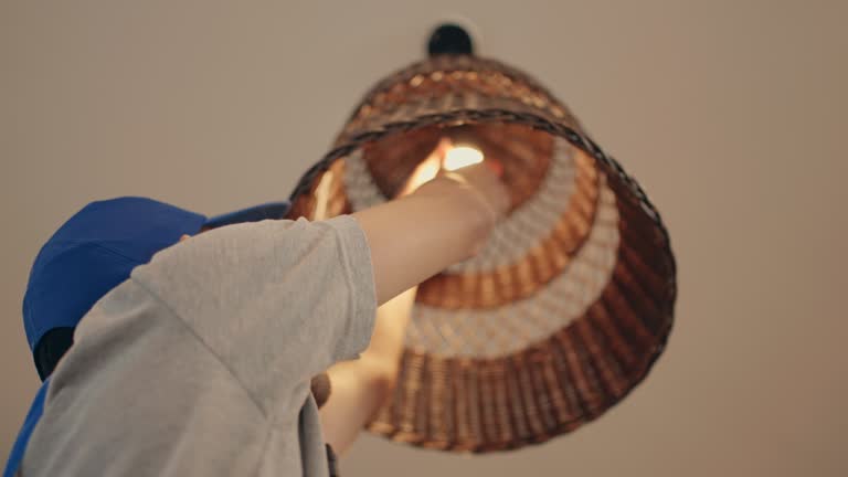 Experienced Male Electrician Installing Light Bulb in Customer's Home