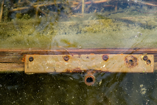 Old wooden sunken boat. A rusty metal hook for an oar underwater. Copy space.