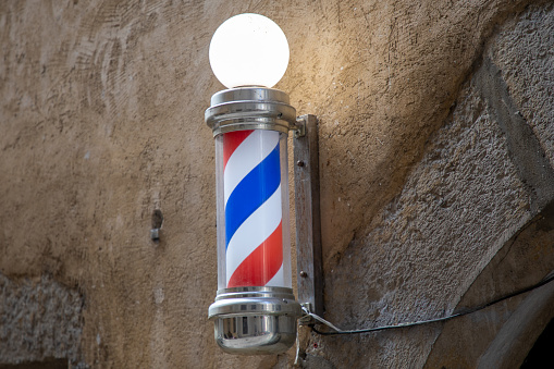 barber pole shop signboard cylindrical sign with light round in vintage hairdresser wall white red blue colors