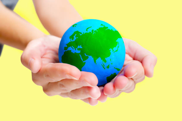 istock Hand Holding a Green and Blue Globe Isolated on Yellow 1505057585