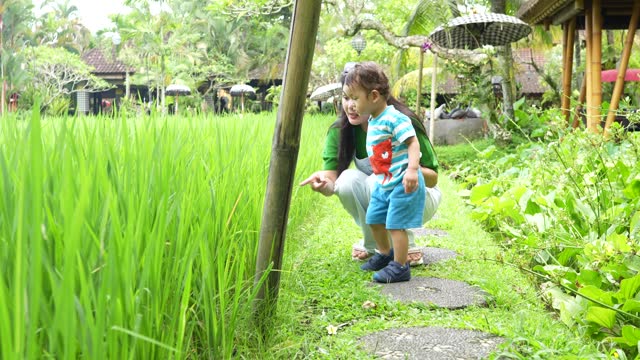 a mother and son in a rice paddy field