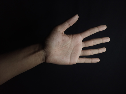 Male hand showing five fingers and palm isolated on black background.