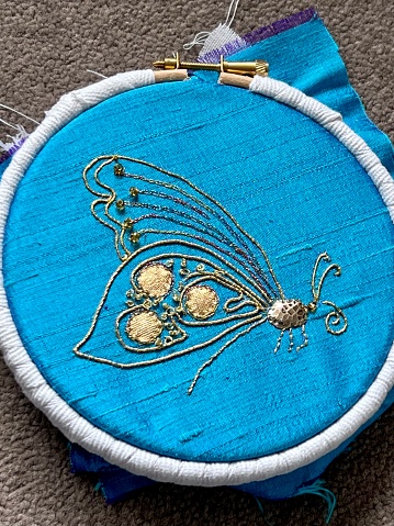 Goldwork and embroidered butterfly on a blue silk dupion background. Embroidery is in an embroidery hoop