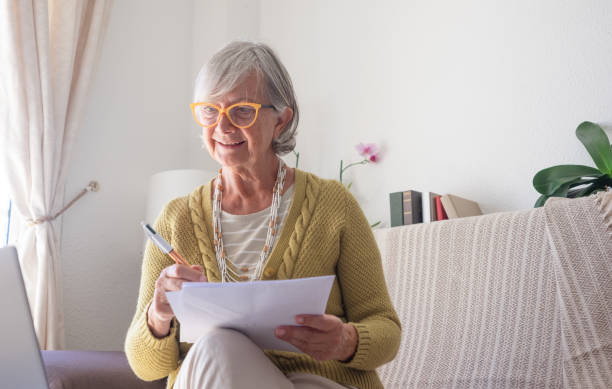istock Active Senior Woman Sitting Indoors in Cozy Sofa Working Using Laptop Browsing the Net. Old smiling Lady Enjoying New Technologies 1505089184