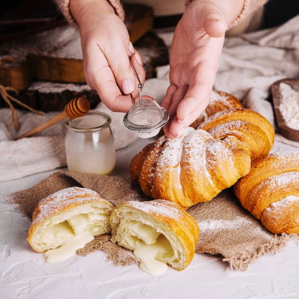 istock woman sprinkles vanilla croissant with powdered sugar 1505089237