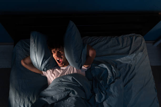 istock Attractive depressed anxious devastated guy lying on bed shouting suffering from insomnia and migraine at night late evening home room. Stress, Insomnia, Anger Cocnept. 1505093656