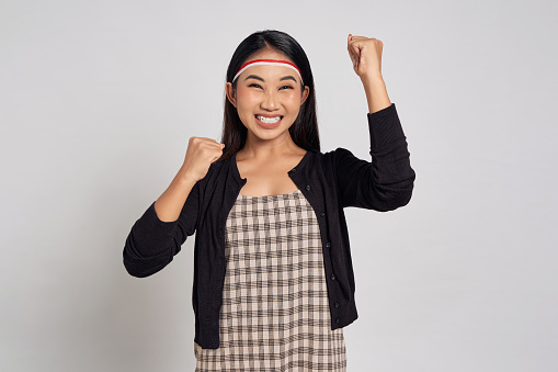 Excited young Asian woman celebrate Indonesia independence day on 17 August and show the spirit and soul of strong nationalism isolated over white background